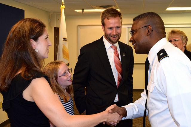 Man shakes hand with woman while a child and another man stand nearby.