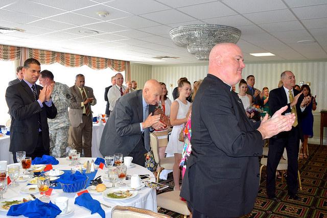 Picture of people giving a standing ovation around banquet tables.