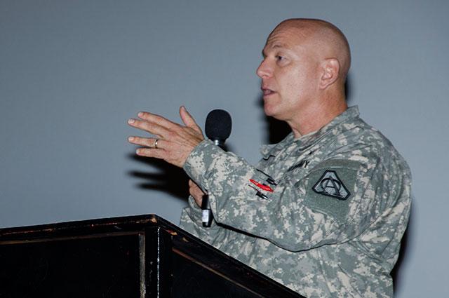 Man speaks into microphone from behind podium.