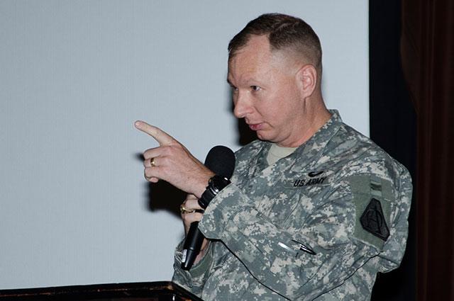 Man gestures while speaking into microphone.